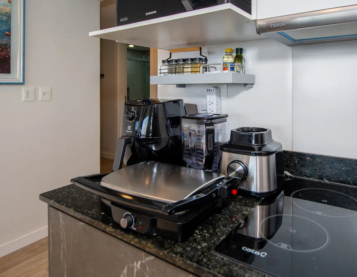 Air fryer, licuadora y mixtera sobre la bancada, con los condimentos arriba