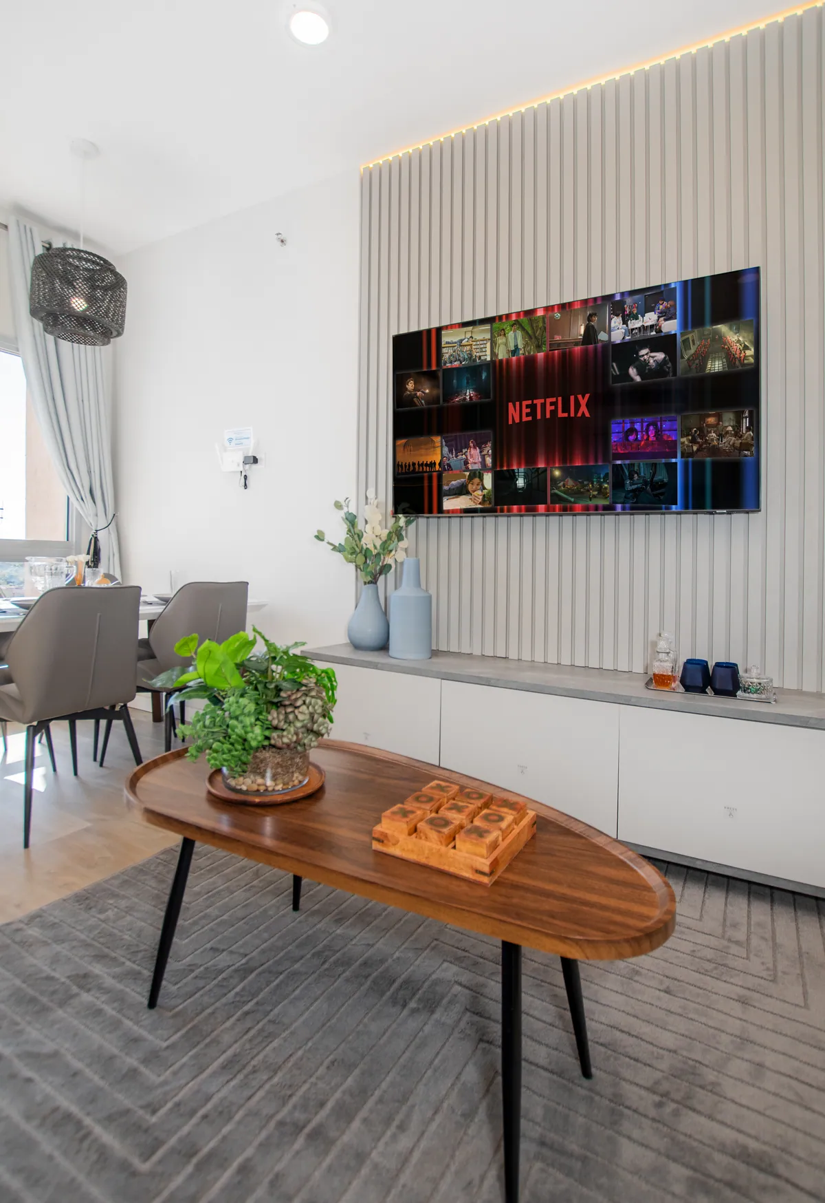 La TV del living sobre el panel de listones, con la mesa ratona adelante