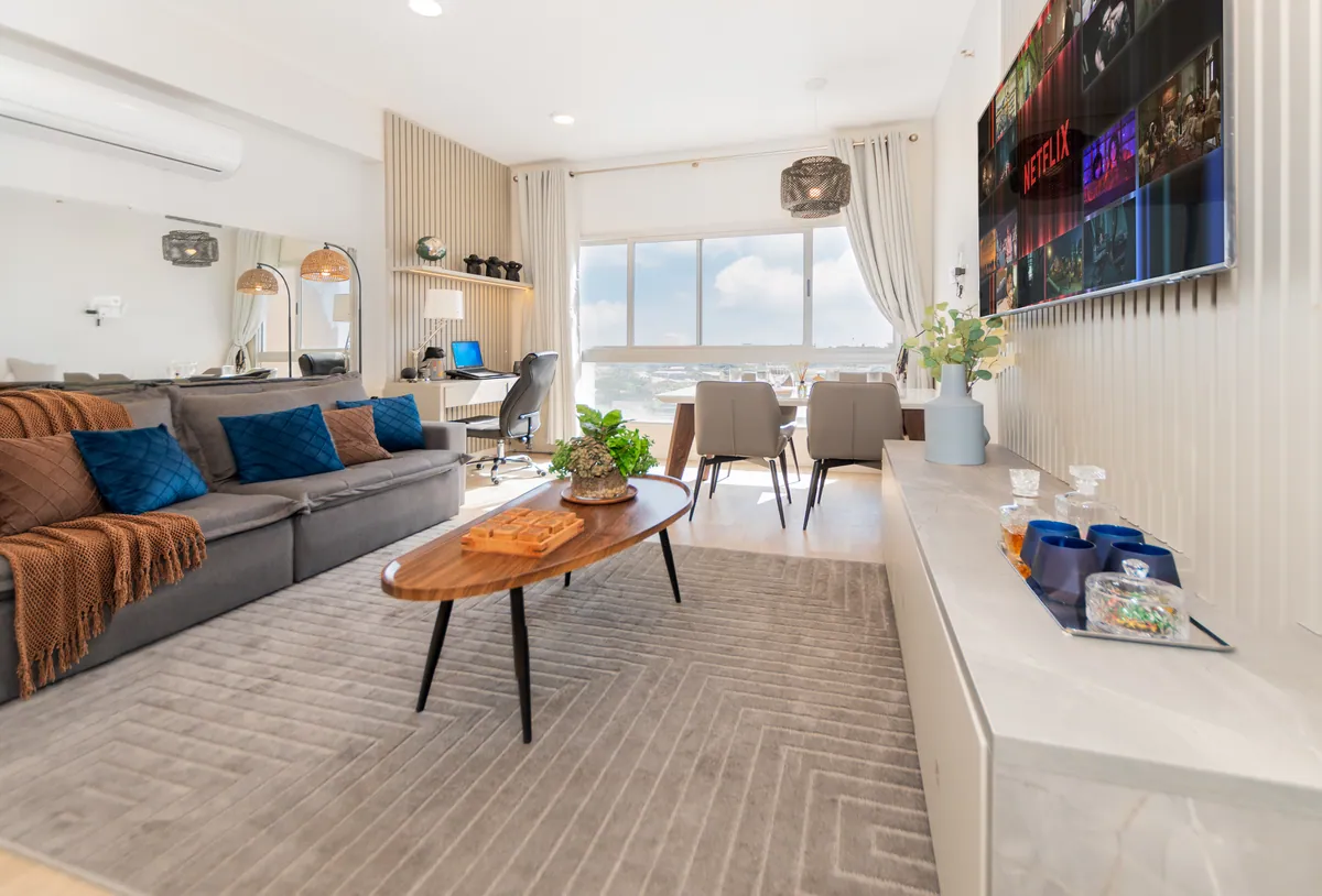 Living con sofá gris, mesa ratona de madera y la ventana con vista al fondo